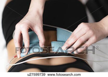 Stock Photo - Placing TENS electrodes on back. Fotosearch
