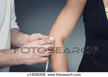 Stock Photo - Placing TENS electrodes on elbow. Fotosearch