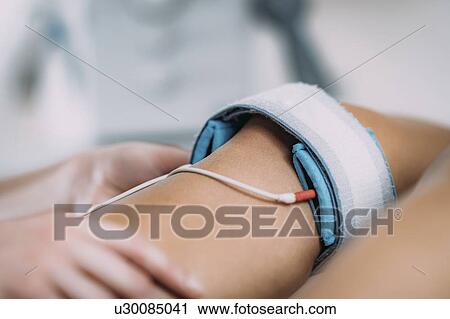 Stock Image - Placing TENS electrodes on knee. Fotosearch