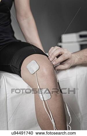 Stock Image - Placing TENS electrodes on knee. Fotosearch