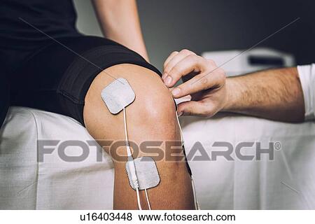 Stock Photo - Placing TENS electrodes on knee. Fotosearch