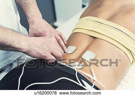 Stock Photo - Placing TENS electrodes on lower back. Fotosearch