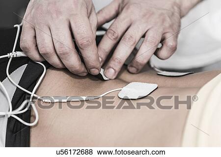 Stock Photo - Placing TENS electrodes on lower back. Fotosearch