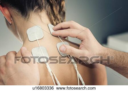 Stock Photograph - Placing TENS electrodes on neck. Fotosearch
