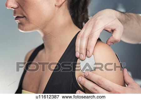 Stock Photo - Placing TENS electrodes on shoulder. Fotosearch