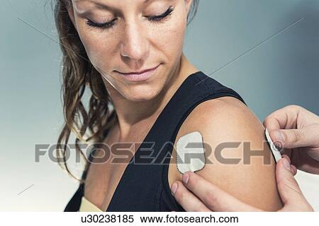 Stock Photography - Placing TENS electrodes on shoulder. Fotosearch