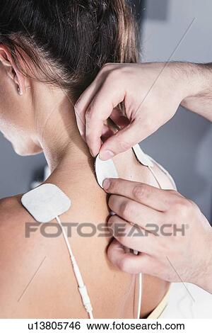 Stock Photograph - Placing TENS electrodes on shoulders. Fotosearch