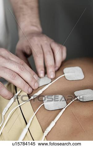 Placing TENS electrodes on upper back View Large Photo Image Stock Photography - Placing TENS electrodes on upper back. Fotosearch