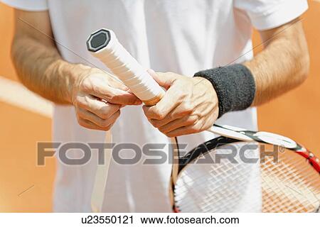 Stock Image - Player putting new grip tape on tennis racket. Fotosearch