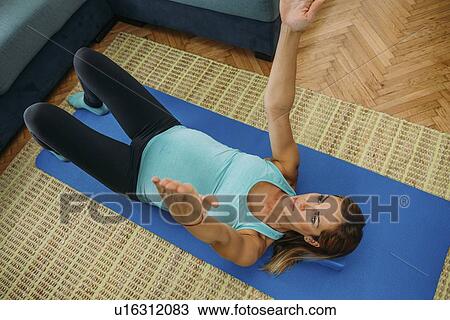 Stock Image - Pregnant woman doing yoga at home. Fotosearch