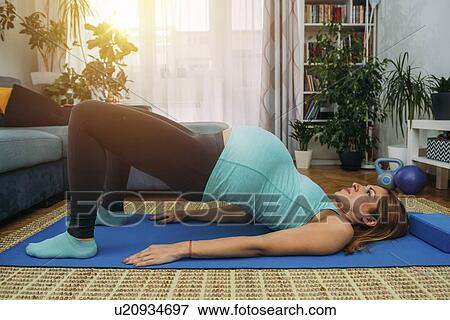 Pregnant woman doing yoga at home View Large Photo Image Stock Photo - Pregnant woman doing yoga at home. Fotosearch