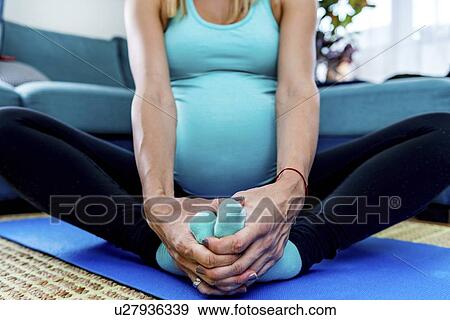 Stock Photo - Pregnant woman doing yoga at home. Fotosearch
