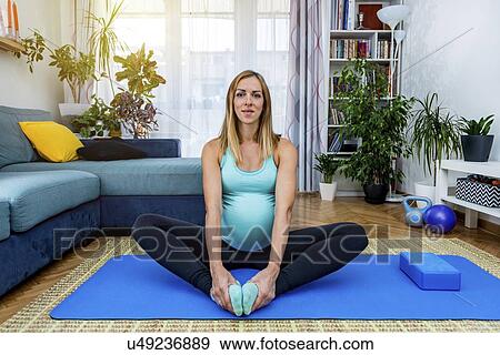 Stock Photo - Pregnant woman doing yoga at home. Fotosearch