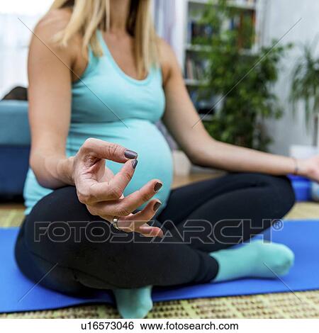 Stock Photograph - Pregnant woman doing yoga at home. Fotosearch