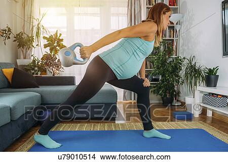 Picture - Pregnant woman exercising at home. Fotosearch