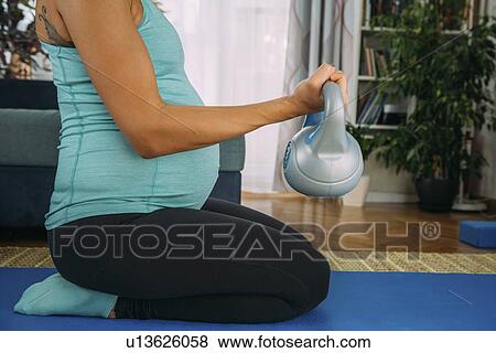 Stock Photo - Pregnant woman exercising at home. Fotosearch