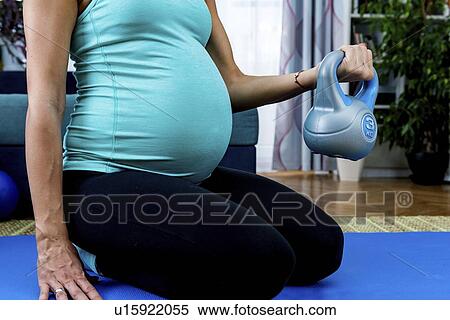 Stock Photography - Pregnant woman exercising at home. Fotosearch