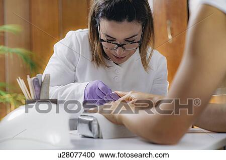 Stock Image - Removing fingernail cuticles. Fotosearch