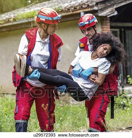 Stock Image - Rescue team evacuate woman from house. Fotosearch