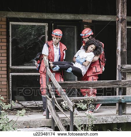 Picture - Rescue team evacuating woman from house. Fotosearch