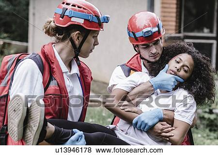 Stock Photo - Rescue team evacuating woman from disaster area. Fotosearch