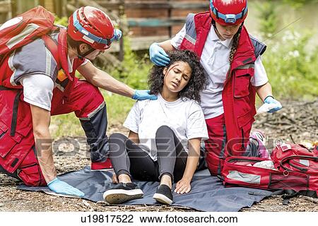 Stock Image - Rescue team helping injured woman. Fotosearch