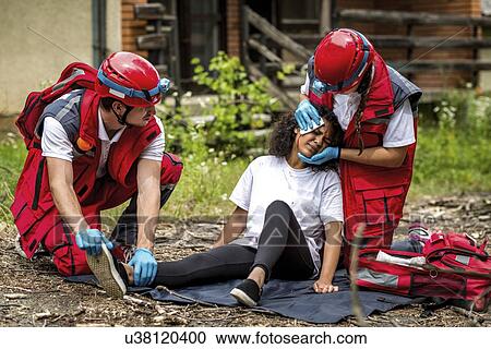 Stock Image - Rescue team helping injured woman. Fotosearch