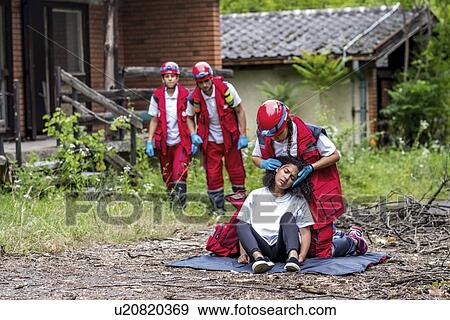 Stock Photo - Rescue team helping injured woman. Fotosearch