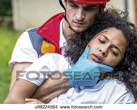 Picture - Rescue worker evacuating woman from house. Fotosearch