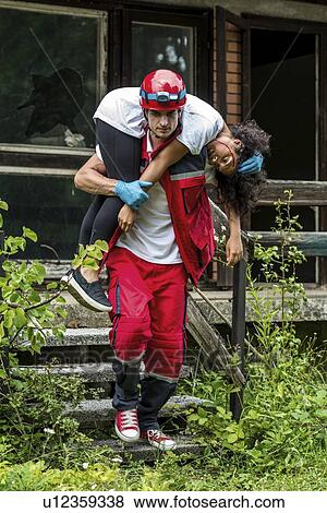 Stock Photo - Rescue worker evacuating woman from house. Fotosearch