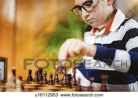 Stock Image - Schoolboy playing chess. Fotosearch