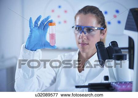Stock Photo - Scientist holding liquid sample. Fotosearch