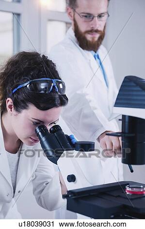 Stock Image - Scientist using microscope. Fotosearch