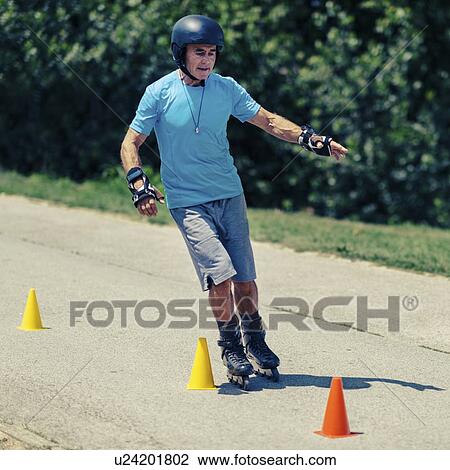 Stock Image - Senior man roller skating in park. Fotosearch