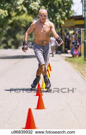 Stock Image - Senior man roller skating in park. Fotosearch