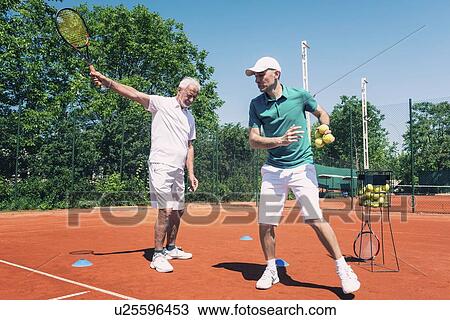 Stock Image - Senior man with tennis instructor. Fotosearch