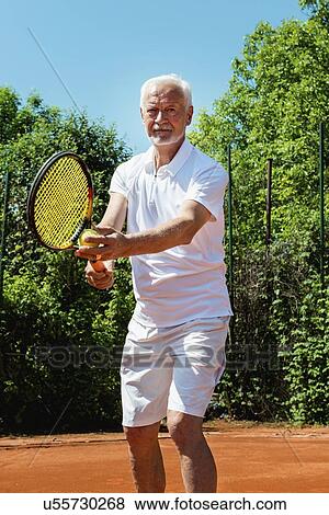 Stock Photo - Senior tennis player serving. Fotosearch