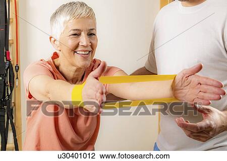 Stock Image - Senior woman exercising with resistance band. Fotosearch