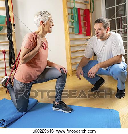 Stock Image - Senior woman exercising with resistance band. Fotosearch
