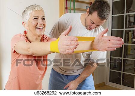 Stock Image - Senior woman exercising with resistance band. Fotosearch