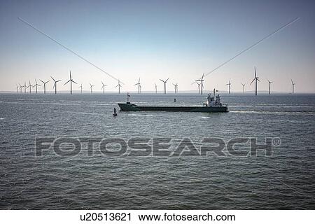 Stock Image - Ship passing wind turbines. Fotosearch