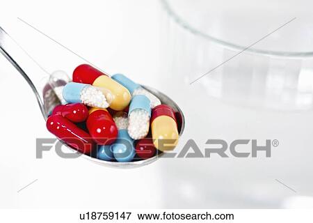 Stock Photo - Spoonful of multicolored capsules. Fotosearch