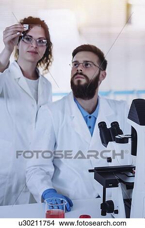 Picture - Students looking at microscope slide. Fotosearch