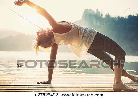 Stock Image - Sunset yoga by the water. Fotosearch