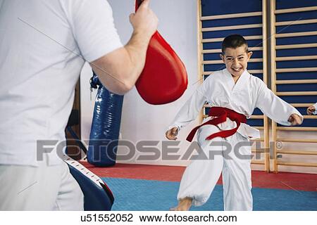 Stock Image - Taekwondo instructor working with boy. Fotosearch
