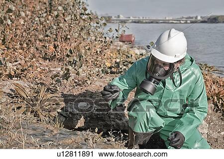 Stock Image - Taking sample of polluted mud. Fotosearch