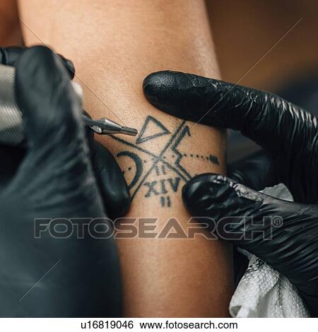 Stock Photograph - Tattoo artist at work. Fotosearch