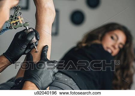 Stock Photograph - Tattoo artist at work. Fotosearch