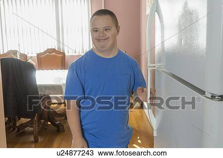 Stock Image - Teen boy with Down Syndrome opening refrigerator. Fotosearch