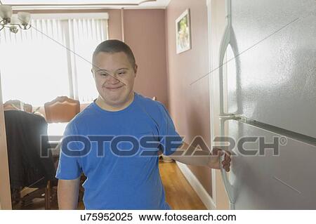 Stock Photography - Teen boy with Down Syndrome opening refrigerator. Fotosearch